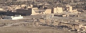  Российские тележурналисты, побывавшие на днях в этой провинции, рассказывают, что власти продолжают усилия по восстановлению инфраструктуры города Тадмор, расположенного в оазисе посреди Сирийской пустыни в 215 километрах к северо-востоку от Дамаска. Руины древней Пальмиры, Всемирного наследия ЮНЕСКО, находятся всего на расстоянии около 500 метров к юго-западу от современного центра города. Хасан укладывает плитку из того же материала, из которого его предки строили этот гостевой дом в Пальмире. Осталось ещё немно- го – и здание, разрушенное бомбёжками, снова сможет принимать своих постояльцев. Рабочие усердно трудятся каждый день, приближая трогательный момент открытия. «Нам осталось отремонтировать пару помещений и сделать небольшое кафе на террасе, на втором этаже. Всё остальное готово», – говорит Махмуд Асад. Здесь уже практически всё восстановлено, как и было прежде. В этом гостевом доме всего 12 номеров. До войны он пользовался популярностью у постояльцев из других стран. Пока идёт финишная отделка, гостевой дом уже принял первых посетителей. Это группа учёных из Российской академии наук. Владелец дома говорит, что будто заново родился. «Эта стройка вернула мне и вообще горожанам надежду на то, что Тадмор скоро станет прежним. Я уже и не помню, когда работал с таким хорошим настроением, как сейчас, на этом объекте. Мы всё сделаем для того, что бы вернуться к нашему образу жизни», – пообещал каменщик Хасан Хайдар. «Невеста пустыни» – Пальмира спустя три года после освобождения от боевиков «Исламского государства» (террористическая организация, запрещённая в РФ) снова начинает приобретать свой прежний облик. Пока одни готовят дома и улицы к приезду туристов, другие готовятся их встречать и развлекать. Можно сказать, что культурная жизнь уже вернулась в Пальмиру. В её древних амфитеатрах, как и раньше, проводят спектакли и дают концерты. Знаменитая на весь мир акустика этих античных сооружений всё такая же, как и тысячу лет назад. «Здесь всегда проводились лучшие концерты, мероприятия международного уровня. Мой оркестр приехал сюда впервые за все последние годы, и это, конечно, невероятное ощущение. Пальмира для меня и многих других музыкантов – источник вдохновения, она нам очень нужна», – заверил начальник оркестра Хасан Аль-Абад. Послушать эти концерты раньше приезжали люди со всего мира. Как только гостиницы будут достроены, в некогда прекраснейшем городе Сирийской пустыни снова ждут наплыва туристов. Поэтому огромное значение имеет и восстановление инфраструктуры.  Городская больница уже работает практически в полноценном режиме. В ней функционируют диагностический кабинет, рентген, лаборатория анализов. Обновлена операционная, в родильном отделении стоит новейшее оборудование, а в реанимации дефибрилляторы и аппарат ИВЛ. Но пока остаётся проблема с персоналом. «До войны тут было 14 врачей и 325 младших медиков, а сейчас из врачей только я один и 150 младших медиков. Большинство уехали, кто-то ушёл на пенсию по старости, кто-то погиб», – признался главврач больницы в Пальмире Валид Аули. Конечно, жители пока надеются на внутренних туристов из Дамаска, Хомса, Латакии и других значимых городов, но в скором времени готовы будут принять и соседей из Иордании, Ливана и остальных арабских стран. В городе уже открыты несколько СТО для ремонта машин. Конечно, пока Пальмира не совсем может предстать перед гостями в своей величественной красоте. Послевоенные пейзажи здесь ещё видно повсеместно, но жители рассчитывают со временем всё восстановить. А пока главное – разместить туристов и обеспечить доступ в Старый город.  Наша справка. В настоящее время в 345 населённых пунктах провинций Алеппо, Дамаск, Дейр-эз-Зор, Деръа, Латакия, Ракка, Хама, Хомс, Эль-Кунейтра и Эс-Сувейда ведутся работы по восстановлению и ремонту 2673 жилых домов, 225 школ, 178 дошкольных и 243 медицинских учреждений, 211 хлебопекарен, 203 электроподстанций, 283 водонасосных станций и 89 культовых сооружений.  * * * Российский Центр по примирению враждующих сторон и контролю за перемещением беженцев в САР продолжает работу, направленную на невоенное разрешение конфликта и оказание всесторонней помощи сирийским гражданам в восстановлении мирной жизни. На днях представителями ЦПВС была проведена гуманитарная акция в населённом пункте Тасиль провинции Дамаск, в ходе которой населению выдано 500 продовольственных наборов общим весом 4,1 тонны. Всего с начала процесса урегулирования российским ЦПВС проведено 3027 гуманитарных акций. Сирийским гражданам доставлено и распределено 5298,86 тонны продовольствия, бутилированной воды и предметов первой необходимости. Продолжается выполнение положений российско-турецкого меморандума о взаимопонимании», принятого 22 октября 2019 года. На минувшей неделе состоялось очередное совместное российско-турецкое патрулирование в провинции Хасеке от пункта пропуска «Шейрек» до Киддла и обратно. Как сообщил на брифинге в пятницу заместитель руководителя российского ЦПВС контр-адмирал Вадим Кулить, на участке трассы М4 между населёнными пунктами Айн-Иса (провинция Ракка) и Телль-Тамер (провинция Хасеке) российской военной полицией за сутки обеспечено безопасное перемещение 863 человек и 391 автомобиля. В юго-западной провинции проводятся мероприятия по стабилизации обстановки. При посредничестве российского ЦПВС в населённых пунктах Альма, Эс-Савара, Эль-Харак, Бусра-Эль-Харири, сказал на брифинге в субботу контр-адмирал Вадим Кулить, за сутки урегулировали свой статус 246 человек, сдано 86 единиц оружия, более 1 тыс. боеприпасов. Днём ранее в этих же населённых пунктах урегулировали свой статус 199 человек, ими сдано 108 единиц оружия и свыше двух тысяч боеприпасов.  * * * Шестой раунд дискуссий малой группы Сирийского конституционного комитета завершился в пятницу в Женеве. После девятимесячного перерыва делегаты в течение пяти дней, с 18 по 22 октября, обсуждали принципы, которые должны быть в новой конституции Сирии. В частности, речь шла о закреплении верховенства права, разделении властей, положении армии и государственных служб безопасности, борьбе с терроризмом и экстремизмом. В состав малой, или редакционной, группы Сирийского конституционного комитета (ККС), поясним, входят 45 делегатов – по 15 от правительства, оппозиции и гражданского общества. В свою очередь ККС полного состава состоит из 150 делегатов (по 50 от каждой из трёх групп). Решение о создании этого комитета для выработки рекомендаций по внесению поправок в конституцию республики было принято на состоявшемся 31 января 2018 года в российском Сочи Конгрессе сирийского национального диалога. Спецпредставитель Президента РФ по Сирии Александр Лаврентьев заявил в пятницу журналистам, что дискуссии шестого раунда Сирийского конституционного комитета в Женеве показали, что позиции сторон пока зачастую противоположны, но это не повод разочаровываться в работе комитета.  «Все эти дискуссии показали, что, конечно, позиции сторон остаются до сих пор достаточно сложными и зачастую имеют абсолютно противоположный контекст, – сказал спецпредставитель Президента РФ по Сирии. – Но это не даёт оснований для того, чтобы разочаровываться непосредственно в перспективах дальнейшей работы конституционного комитета». Он добавил, что спецпосланник Генсека ООН по Сирии Гейр Педерсен после дискуссий выразил надежду на преодоление имеющихся трудностей и организацию дальнейших встреч. Александр Лаврентьев признал, что на дискуссиях в среду «не обошлось без определённых озабоченностей», связанных с террористическим актом в Дамаске, в результате которого погибли 17 сирийских военнослужащих.  «Поэтому в среду стороны перешли опять на язык взаимных обвинений. Но тем не менее благодаря работе спецпосланника и его офиса эту негативную тенденцию удалось преодолеть и в четверг вернуть в конструктивное русло работу Конституционного комитета», – отметил он. В целом же нельзя сказать, что встреча прошла «полностью результативно», констатировал Александр Лаврентьев. Среди позитивных моментов он отметил то, что «стороны начали говорить друг с другом. Прошёл целый ряд встреч сопредседателей, в ходе которых пытались договориться о позициях сторон и о том, как нужно работать над обсуждением того или иного принципа». Предложение Педерсена о проведении очередного раунда консультаций Сирийского конституционного комитета в Женеве 22 ноября «остаётся на столе» и представляется российской стороне наиболее оптимальным, заявил Александр Лаврентьев.  «22 ноября я считаю вполне приемлемой датой. Возможно, по какой-то из причин одну из сторон эта дата не будет устраивать, потому что решения принимаются на основе консенсуса. Наверное, тогда возможен перенос на более позднюю дату, наверное на начало декабря. Но тот вариант, который предложил Педерсен, – провести седьмую сессию 22 ноября, а восьмую сессию 5–6 декабря – наиболее оптимальный», – считает спецпредставитель Президента РФ по Сирии. По его словам, делегация официального Дамаска пока не согласилась на предложения Педерсена провести новые раунды переговоров по конституции Сирии в ноябре и декабре. «Делегация на это добро не дала, сказала, что необходимо изучить ещё вопросы, согласовать, соответственно, с членами делегации», – сообщил Александр Лаврентьев. Спецпосланник Президента РФ указал, что Москва выступает за продолжение работы Конституционного комитета Сирии и подчёркивает необходимость выработки решений, которые позволят достичь конкретных договорённостей по реформе основного закона республики. «Мы, российская делегация, со своей стороны, конечно, приветствуем усилия спецпосланника [Генсека ООН по Сирии Гейра Педерсена], его офиса. Работа проведена значительная, и результаты этой работы мы видим. Изменилась, конечно, это очень приятно осознавать, в целом сама атмосфера взаимодействия между сторонами, но, конечно же, уровень доверия остаётся ещё на достаточно низком уровне, который не позволяет осуществить прорыв в подготовке новой конституции, – добавил он. – Мы со своей стороны, естественно, продолжим оказывать поддержку этому процессу, поддержку спецпосланнику и всем сторонам советуем».